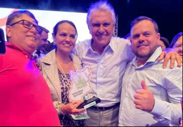 Professora Kelci Tristão Pádua ao lado do vice prefeito Danilo Araújo e do vereador Vanderlon Messias recebendo troféu Secretária de Destaque durante a cerimônia do Prêmio AlfaMais das mãos do governador Ronaldo Caiado 